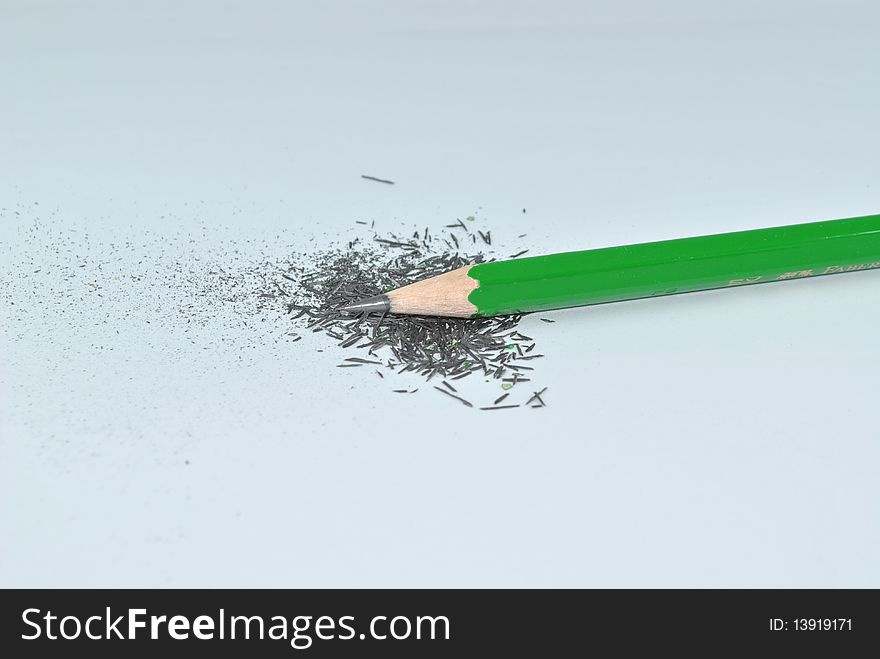 A sharpened green pencil with its shreds. A sharpened green pencil with its shreds.