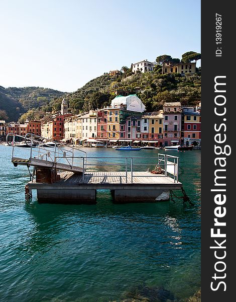 A barge and clear sea in front of the distinctive homes of the village of Portofino