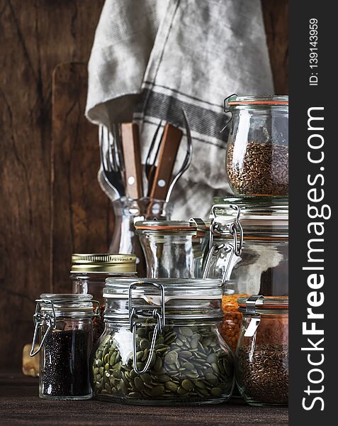 Stocks or set of cereals, pasta, groats, organic legumes and useful seeds in glass jars. Vegan source of protein and energy resources. Healthy vegetarian food. Domestic life scene. Rustic wooden kitchen table background. Selective focus