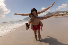 Young Couple Piggyback With Arms Outstretched Taking Selfie Royalty Free Stock Photography