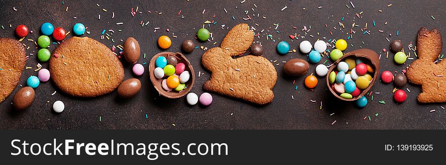 Easter greeting card backdrop with colorful gingerbread cookies, chocolate eggs and candies. Top view on stone table