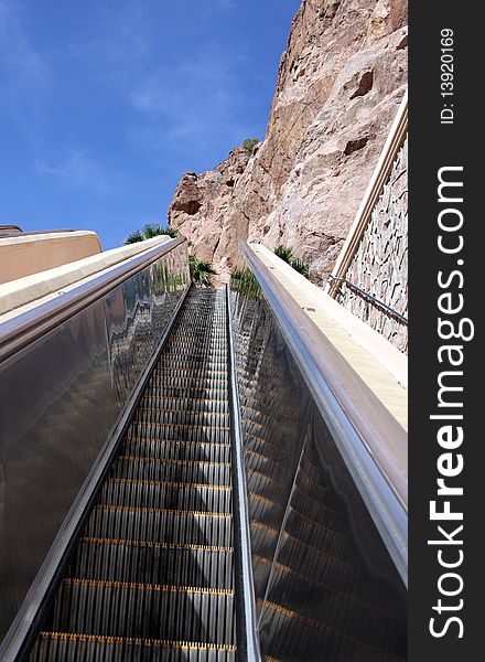 An up escalator near a red rock mountain wall