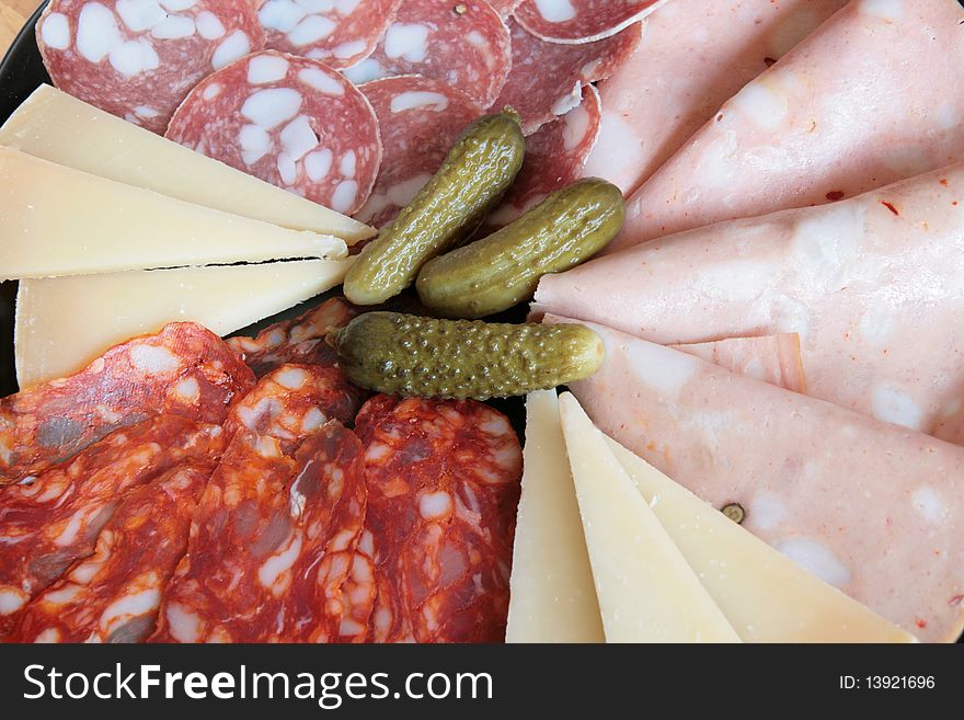 A plate of mixed salami and cheese with cucumbers. A plate of mixed salami and cheese with cucumbers