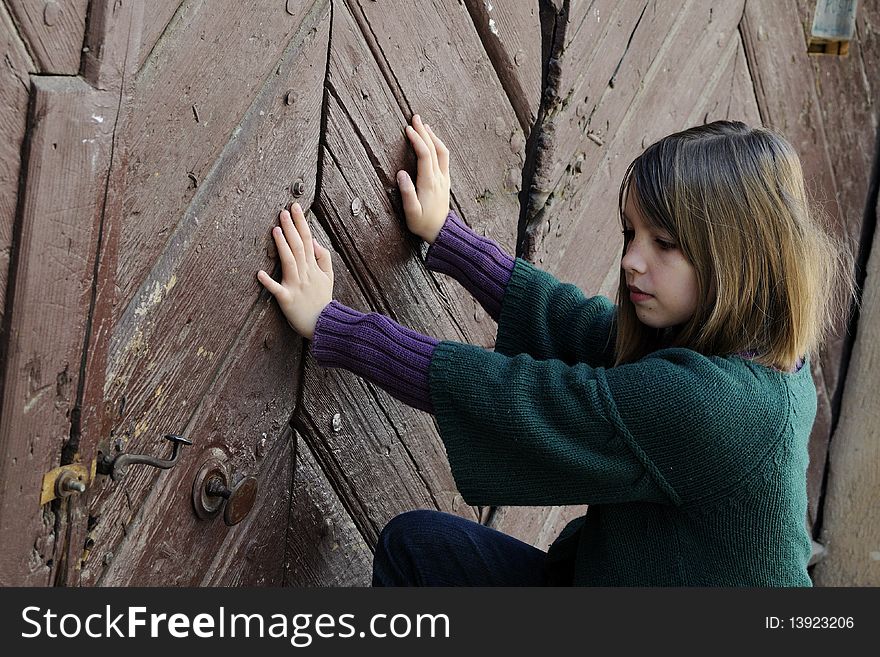 Little girl trying to open old door
