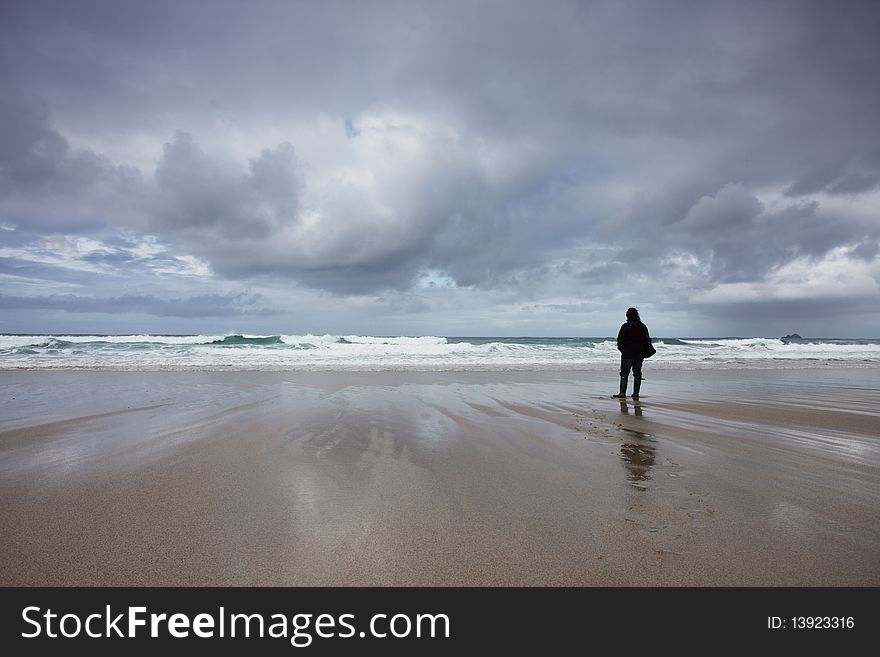 A woman standing on a deserted beach.