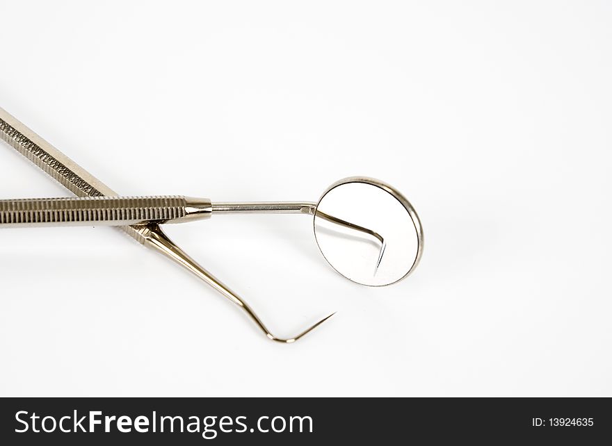 Dental mirror and pick isolated in white. Dental mirror and pick isolated in white