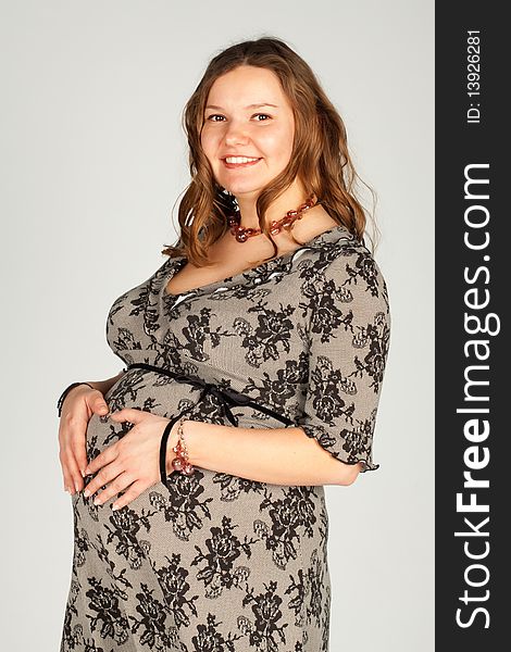 A pregnant woman smiling and keeps his hands on his stomach