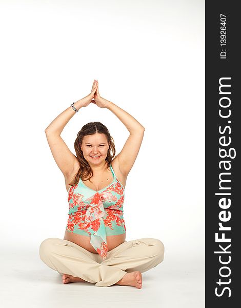 Beautiful smiling pregnant woman doing a yoga in the lotus position. Beautiful smiling pregnant woman doing a yoga in the lotus position.