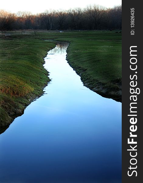 Water with blue sky reflecting at dusk; irrigation ditch on farm. Water with blue sky reflecting at dusk; irrigation ditch on farm
