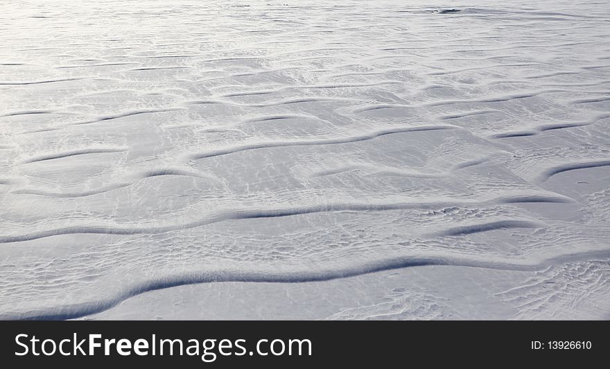 A photo of blowing snow creating patterns on a frozen lake near Anchorage, Alaska.