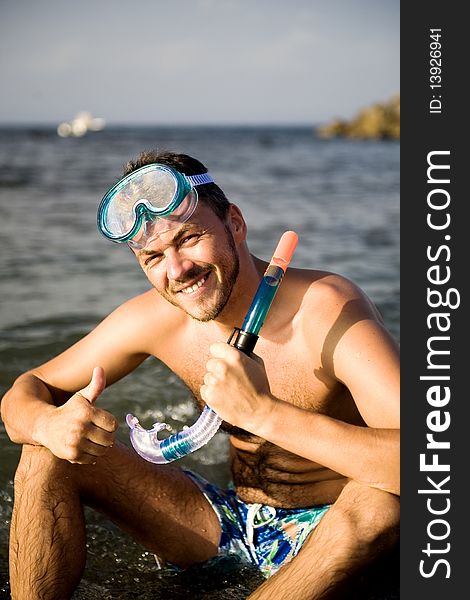 Young happy handsome summer diving man with swimming mask and snorkel preparing to dive in blue sea. Young happy handsome summer diving man with swimming mask and snorkel preparing to dive in blue sea