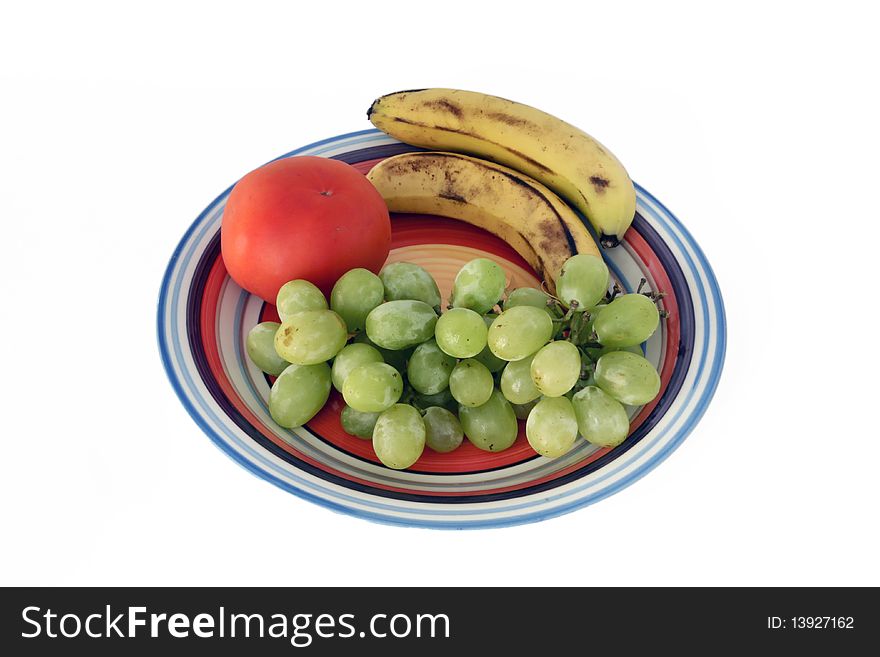 White grapes, bananas and tomato on a plate isolated on a white background