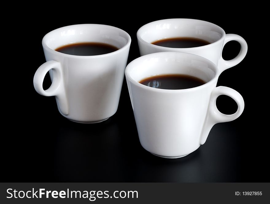 Three white coffee cups  isolated on a black background. Three white coffee cups  isolated on a black background