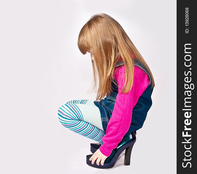 Little girl squatting in adult shoes. Little girl squatting in adult shoes