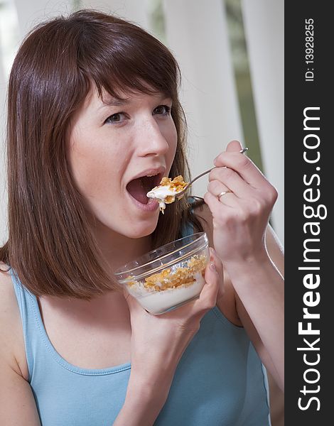 Smiling woman eating corn flakes at home on the sofa