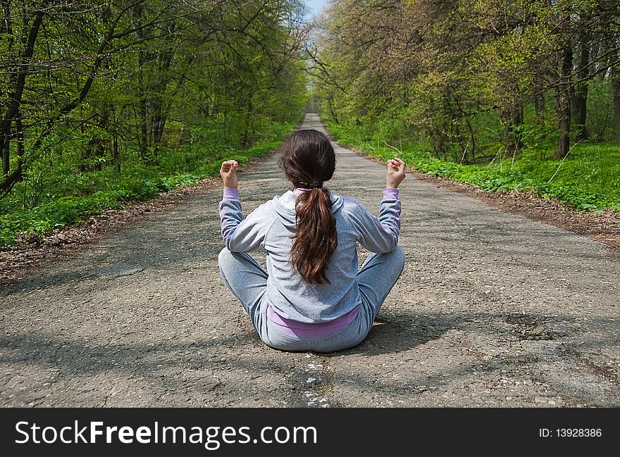 Girl sitting in the middle of the forest road