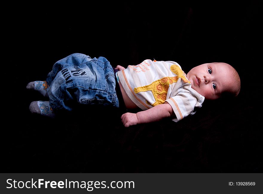 3 Month old baby lying clothed on a black background