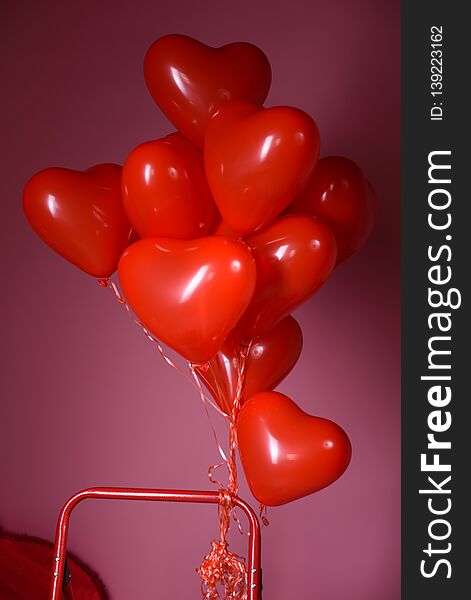 Red heart-shaped balloon on a pink background.//