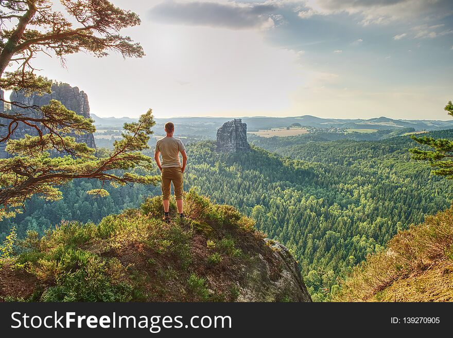 Man hiker on mountain top hiking or climbing. Looking and enjoying inspirational view into landscape