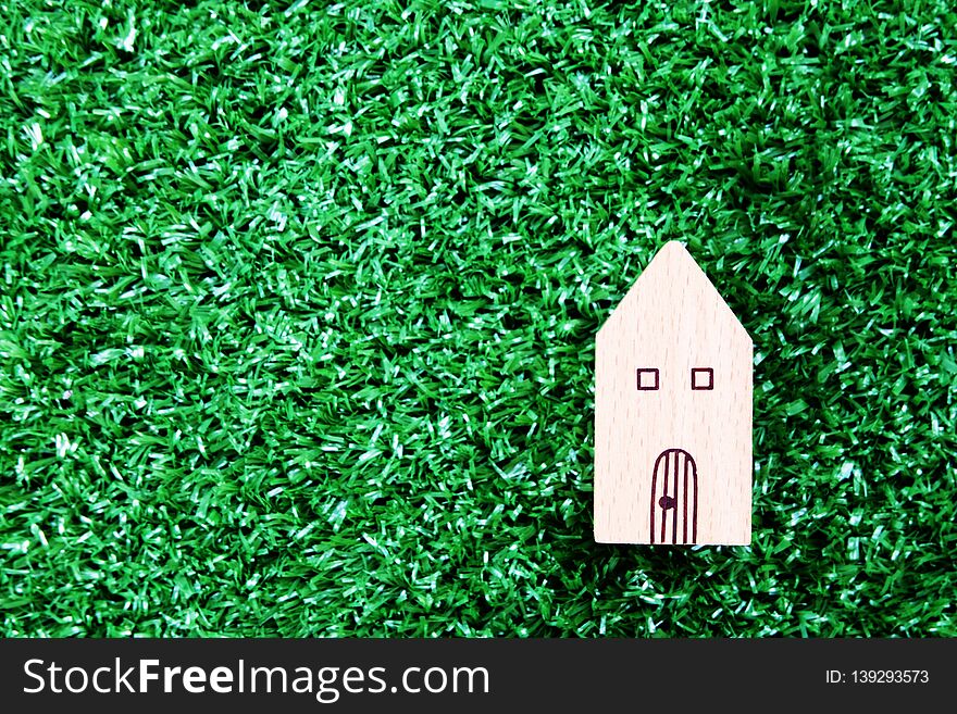 Wooden house model on artificial grass floor. Property investment and house mortgage concept