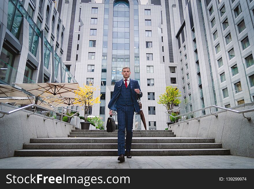 Serious businessman in a checkered stylish suit coming down the stairs. Business life in the city. Portrait of a modern businessman