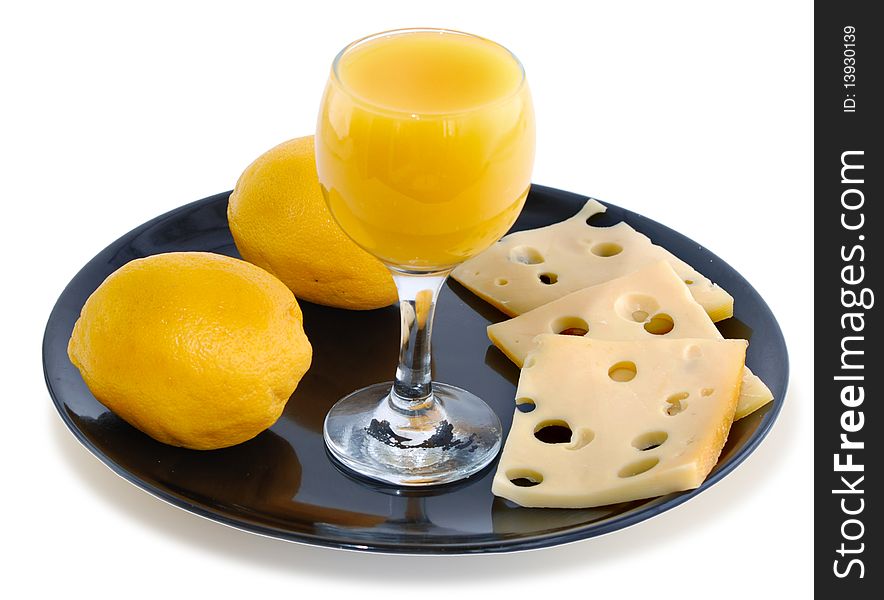 Orange juice in a glass, cheese, lemons on a black plate. Orange juice in a glass, cheese, lemons on a black plate