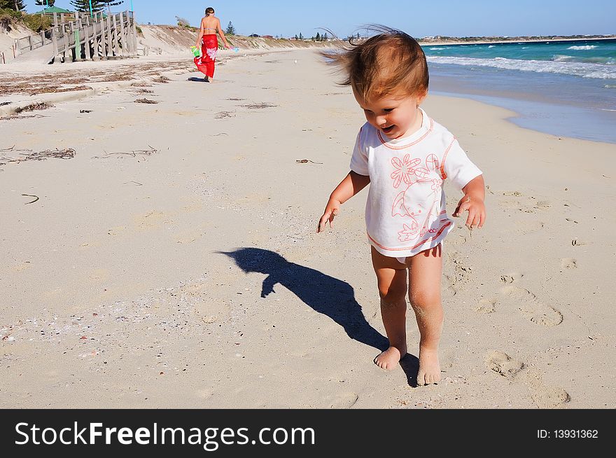 Charming little girl running on the golden beaches near the ocean blue