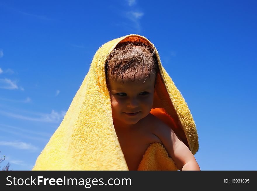 Charming little girl in a yellow towel on the beach as a symbol of childhood happiness and joy