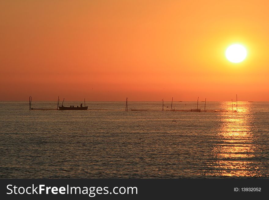 Fishermen throwing their nets in the black sea in the morning while the sun is rising above. Fishermen throwing their nets in the black sea in the morning while the sun is rising above