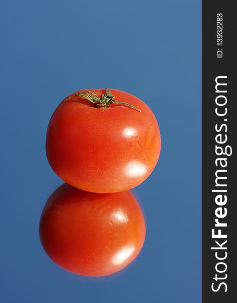Tomato on a mirror, against the blue sky