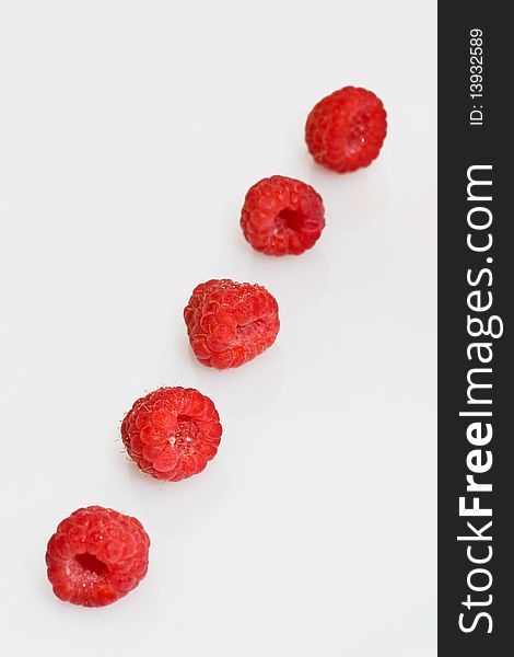 Raspberries in a row on a white background