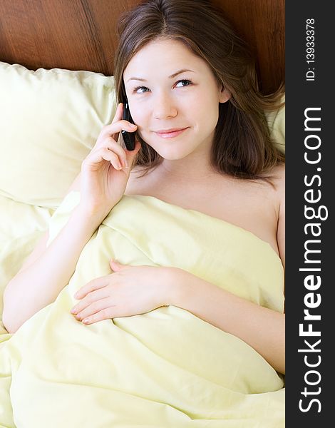 Young beautiful woman with mobile phone in the bed. Young beautiful woman with mobile phone in the bed