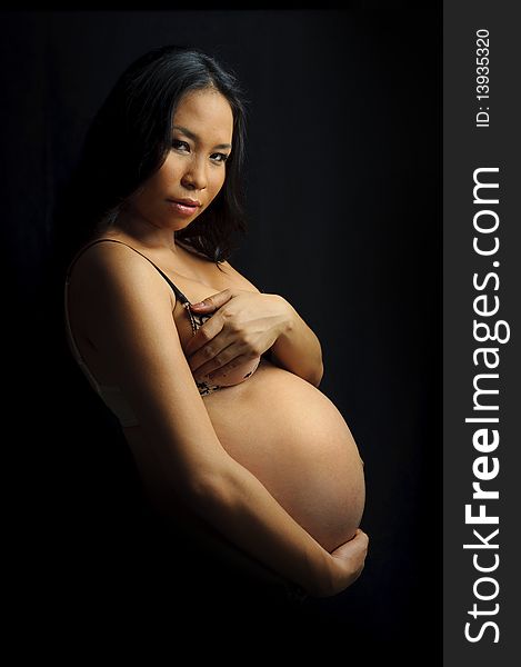Beautiful woman is 9 months pregnant and poses in studio. Beautiful woman is 9 months pregnant and poses in studio