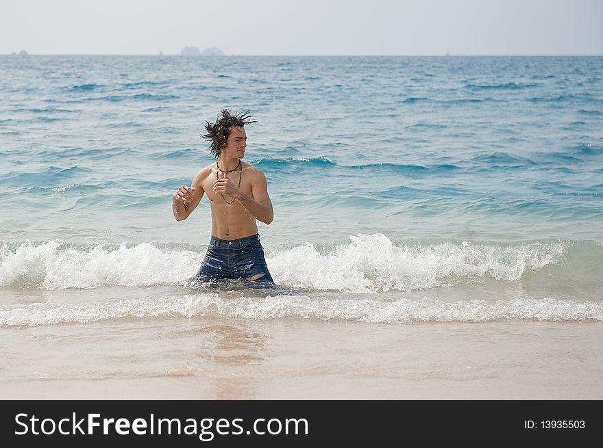 Athletic and muscular man in the surf of the Pacific Ocean shaking his wet hair. Athletic and muscular man in the surf of the Pacific Ocean shaking his wet hair.