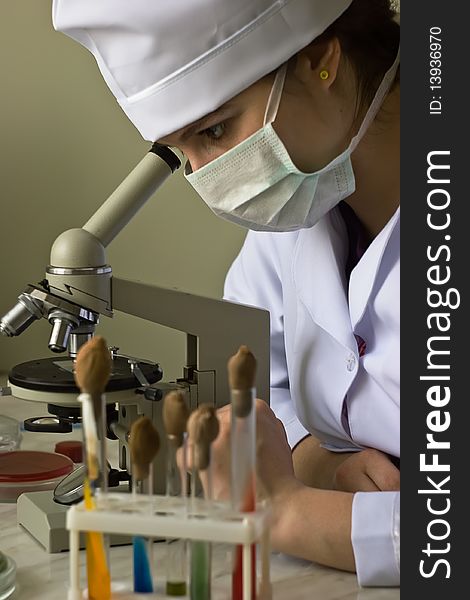 Curious research scientist in lab coat looking at speciment under microscope in laboratory. Curious research scientist in lab coat looking at speciment under microscope in laboratory