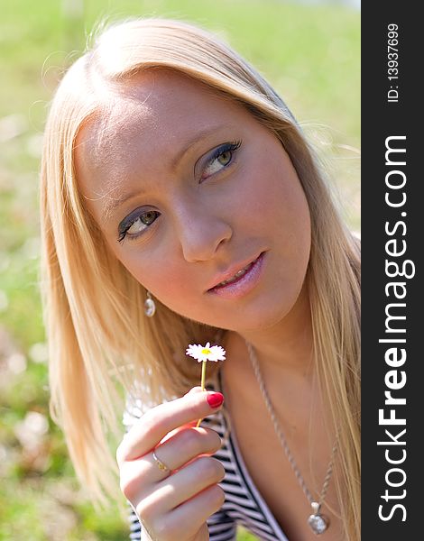 Blond girl in nature holding Daisy flower