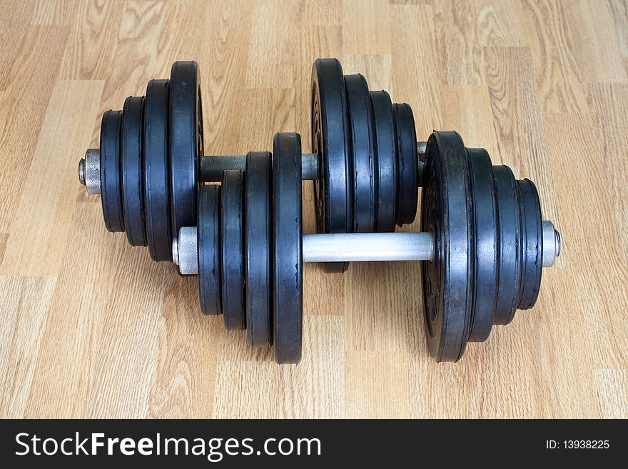 Two old dumbbells on a wood floor. Two old dumbbells on a wood floor