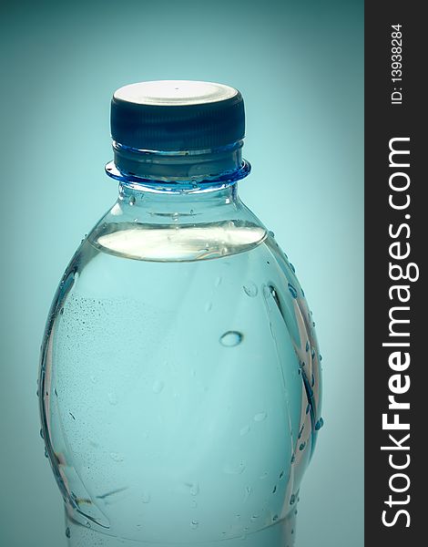 A plastic bottle filled with still water. Image isolated on light blue studio background. A plastic bottle filled with still water. Image isolated on light blue studio background.