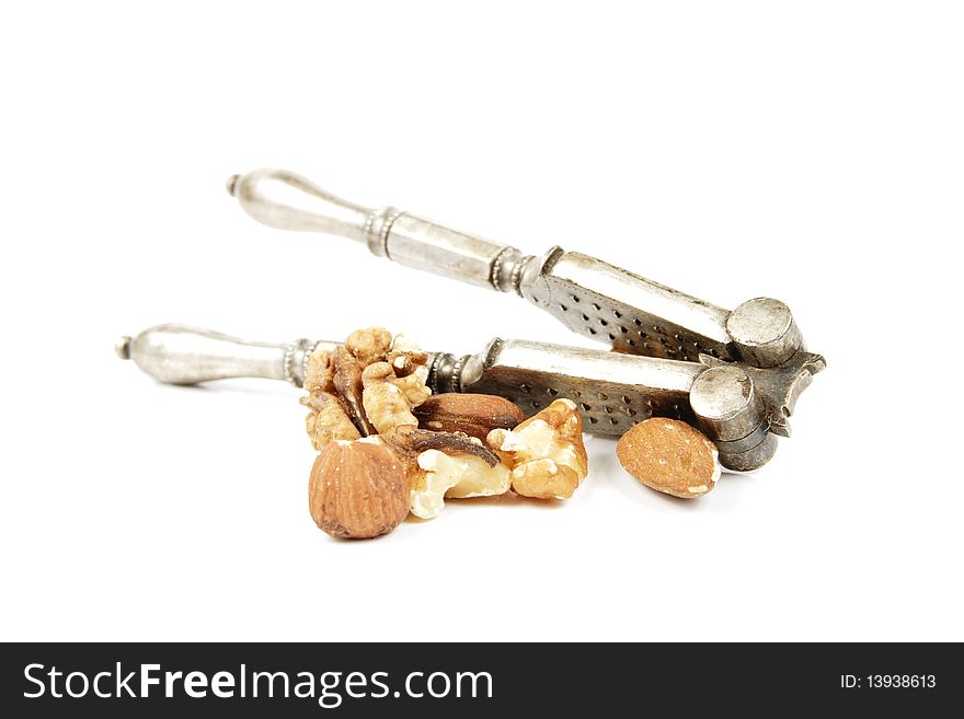 Assorted mixed nuts with a silver nutcracker on a reflective white background. Assorted mixed nuts with a silver nutcracker on a reflective white background