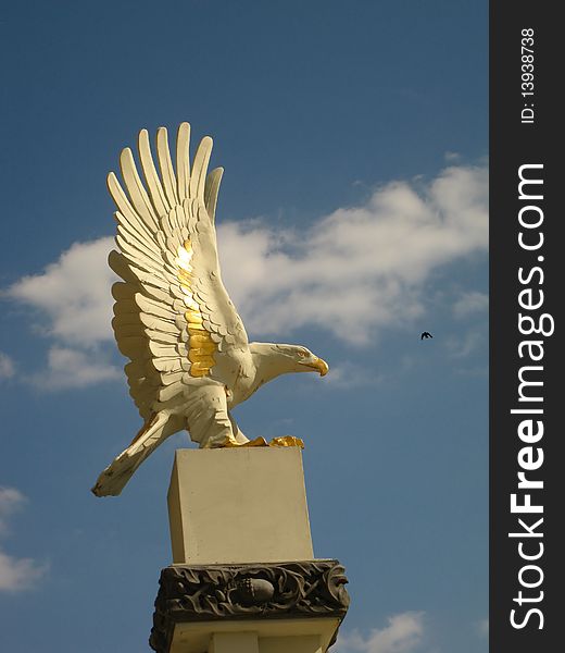 Eagle on a pedestal and a bird in a blue sky