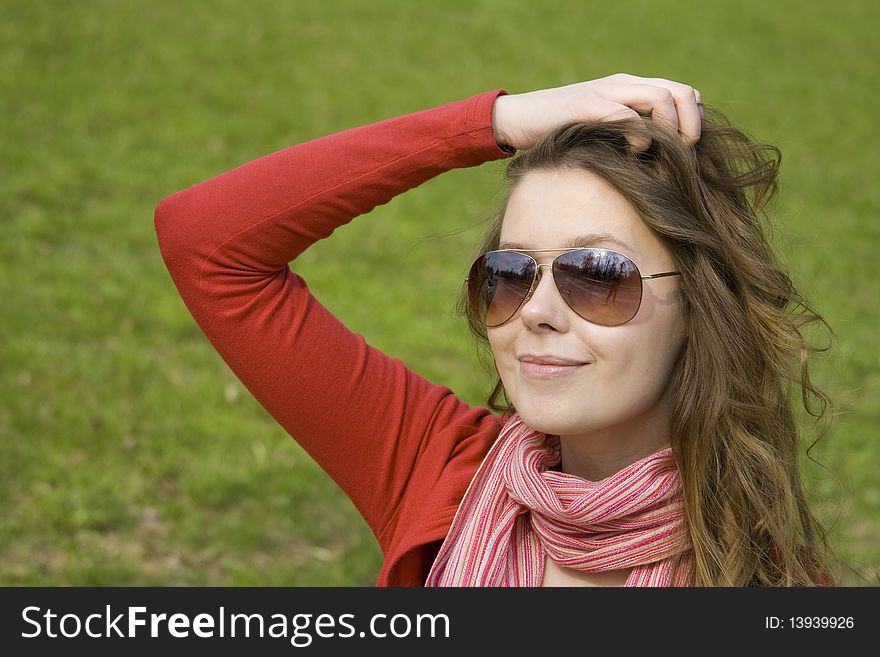 A beautiful young woman in sunglasses relaxing in the park on a bench. Straightens his hair. A beautiful young woman in sunglasses relaxing in the park on a bench. Straightens his hair.