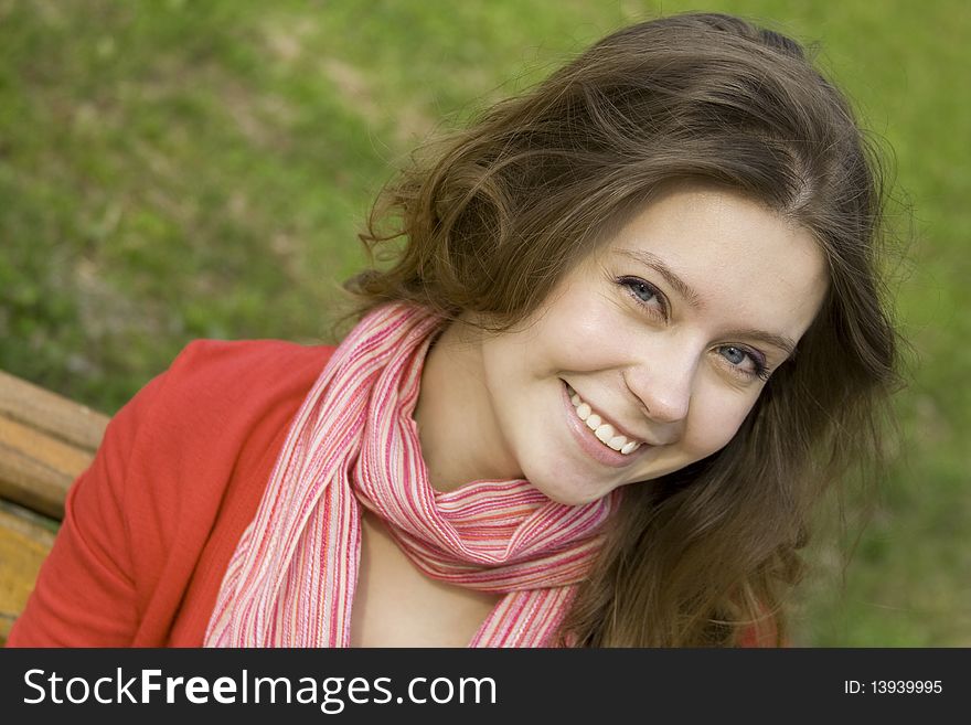 A beautiful young woman relaxing in the park on a bench. Laughs. A beautiful young woman relaxing in the park on a bench. Laughs