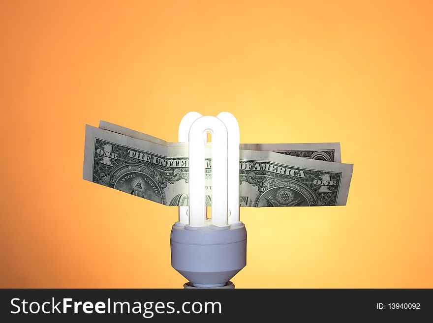Energy saving compact fluorescent lightbulb and one dollar note on ginger background. Energy saving compact fluorescent lightbulb and one dollar note on ginger background