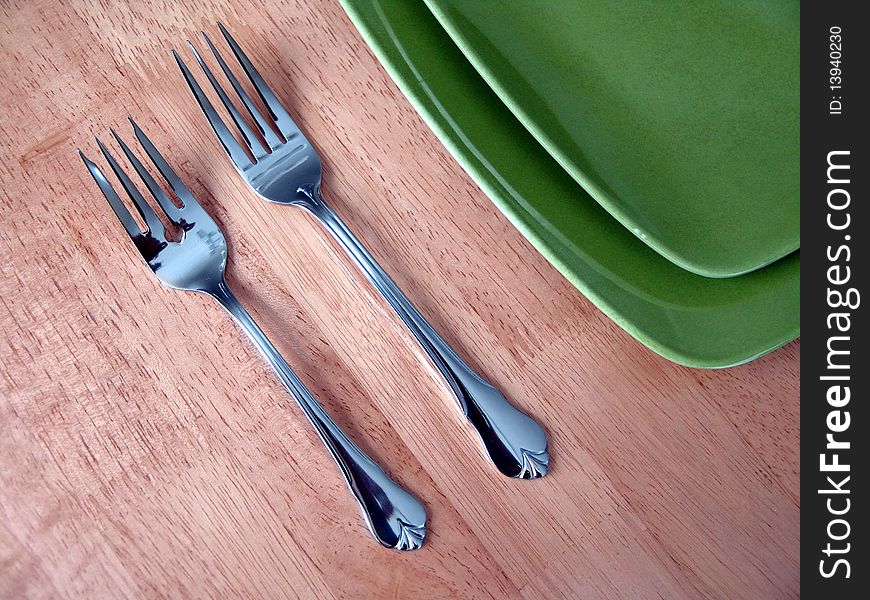 Two forks and green plate over wood table. Two forks and green plate over wood table