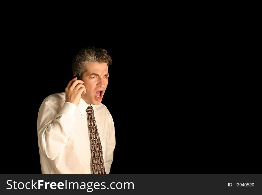 Business man yelling on cell phone on a black isolated background