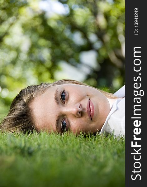 Girl lying on the grass, looking at camera