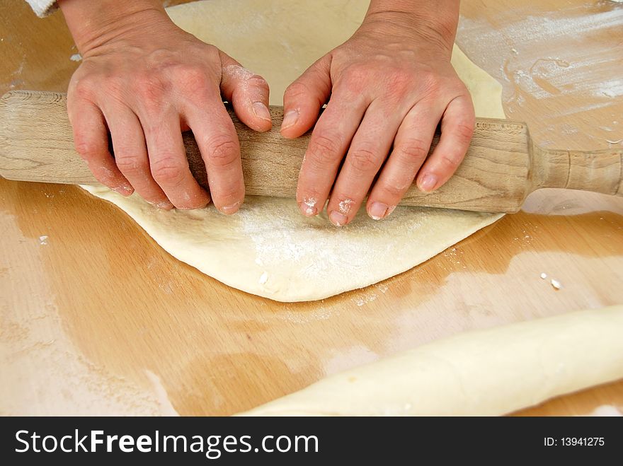 Hands on rolling pin over dough