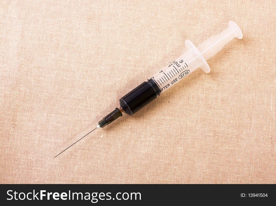 Syringe with brown vaccine on the canvas. Syringe with brown vaccine on the canvas