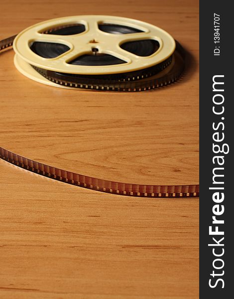 Reel with eitght millimeter film on the wooden table. Reel with eitght millimeter film on the wooden table