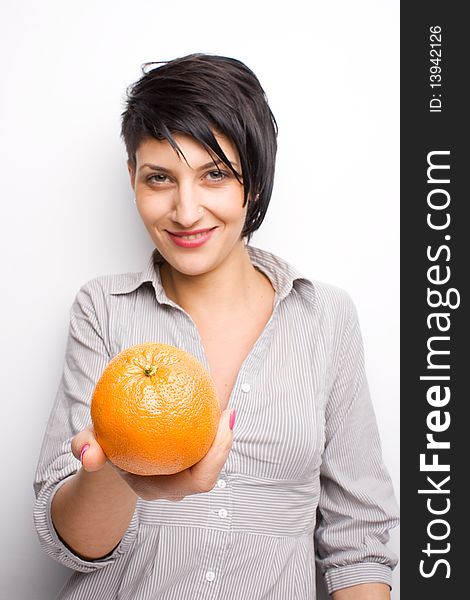 Girl offering a fresh orange (focus on orange). Girl offering a fresh orange (focus on orange)